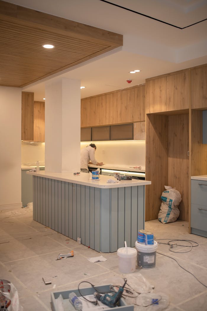 Contemporary kitchen undergoing renovation with wooden cabinets and clean design.